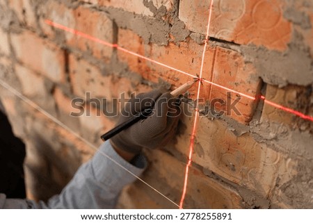 close-up of construction worker marking wall using pencil and laser level during home renovation for control, measure and marking