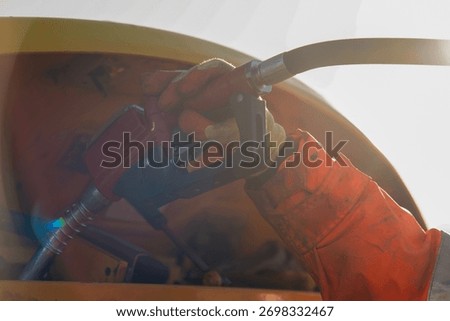 Close-up of Construction worker in safety gloves filling excavator with diesel fuel on building site