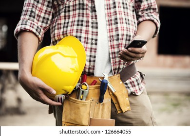 Close-up Of Construction Worker Sending Text On Mobile Phone