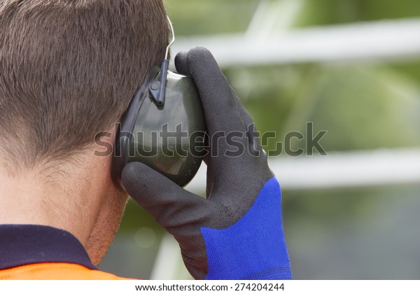 Closeup of construction worker wearing ear\
protectors at storage tank\
park
