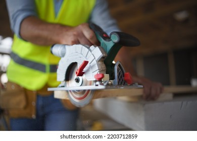 Close-up of construction worker working with eletric saw inside wooden construction of house, diy eco-friendly homes concept.
