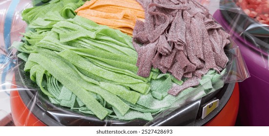 Close-up of a container filled with colorful gummies in green, purple, and orange. The arrangement is visually appealing, creating a vibrant display
 - Powered by Shutterstock