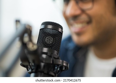 Close-up content creator man host streaming a podcast on laptop set up with headphones and condenser microphone interview guest conversation at broadcast studio. Blogger recording voice over radio - Powered by Shutterstock