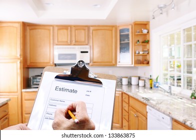 Closeup Of A Contractors Clipboard As He Writes Up An Estimate For A Kitchen Remodel. Shallow Depth Of Field With Focus On Clipboard.