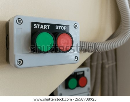 Close-up of control panel with start and stop buttons mounted on wall.