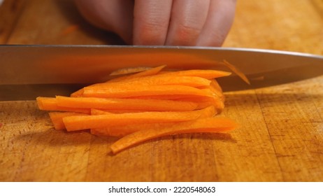 Close-up of a cook professionally slicing carrots on a kitchen board. Side view. The concept of tasty and healthy food - Powered by Shutterstock