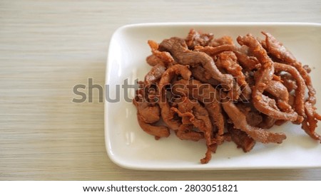 A close-up of cooked beef strips served on a white plate with a green background