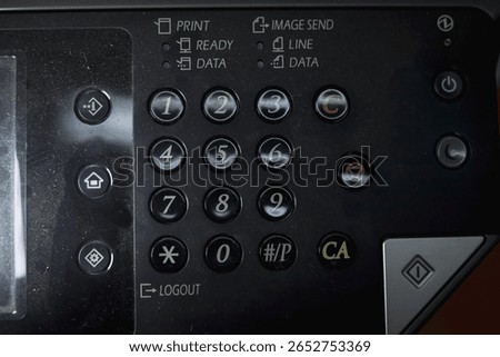 Close-up of a copier or printer control panel, with number pad, function buttons, and status lights for printing and sending images.
