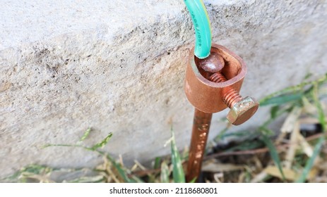 Close-up of copper electrical grounding rods. Metal grounding rods pinned into the ground on the side of the cement floor to prevent short circuits with a copy space. Selective focus - Shutterstock ID 2118680801