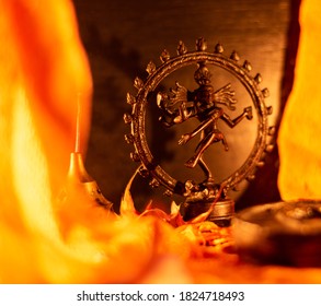 Close-up Of A Copper Figurine Of Shiva Framed By Orange Drapes And Lit By Candle Light