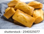 Close-up of corn muffins on plate with bowl of corn meal and additional muffins in the background.