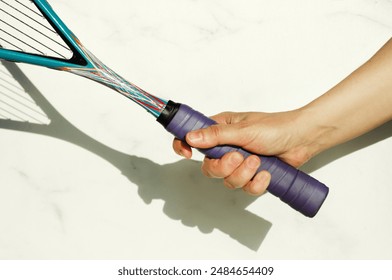 Close-up of the correct grip of a squash racket. Hand holding a racket on a white background, space for text, copy space