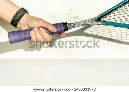 Close-up of the correct grip of a squash racket. Hand holding a racket on a white background, space for text, copy space