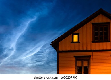 Close-up Of Cottage With One Window Lit Against Dramatic Night Sky