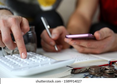 Close-up Of Couple With Calculator And Mobile Phone Planning Budget At Home. Bunch Of Coins On Table Near Notebook. Financial Problems And Economy Concept