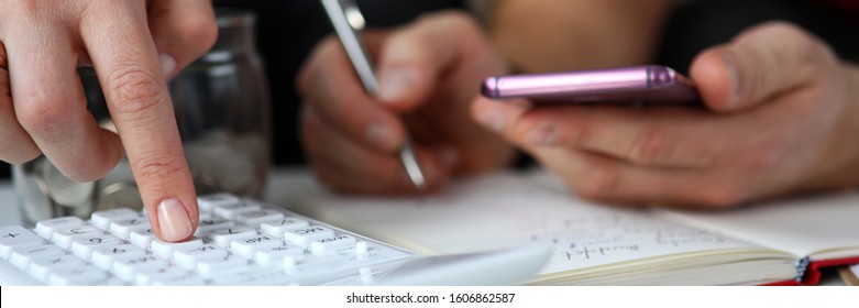 Close-up Of Couple With Calculator And Mobile Phone Planning Budget At Home. Bunch Of Coins On Table Near Notebook. Financial Problems And Economy Concept