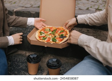 Close-up of Couple grab slices of pizza from box at the outdoor. Man and woman hands taking pizza. Vegan pizza with fresh tomatoes basil and broccoli. Lactose and gluten free - Powered by Shutterstock