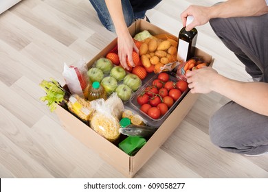 Close-up Of Couple With Groceries In Cardboard Box