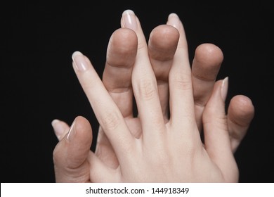 Closeup of couple hands with fingers interlocked together against black background