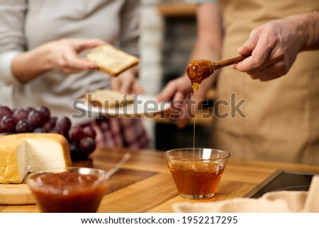 Close-up of couple having honey with toasted bread while eating breakfast at home.