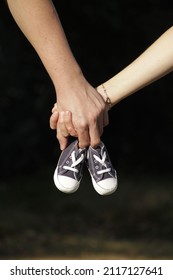 A closeup of a couple holding baby's shoes