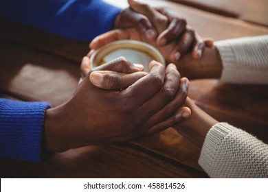 Close-up Of Couple Holding Hands While Having Coffee In Cafeteria