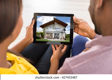 Close-up Of A Couple Looking At House On Digital Tablet