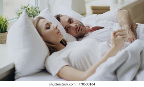 Closeup of couple with relationship problems having emotional conversation while lying in bed at home