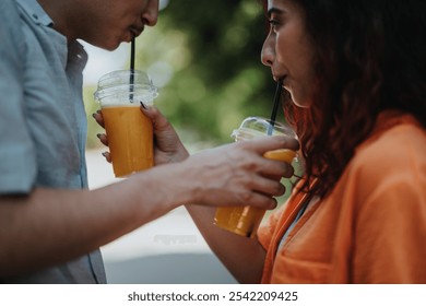 Close-up of a couple sharing a refreshing orange juice together in the park, enjoying a sunny day outdoors. - Powered by Shutterstock