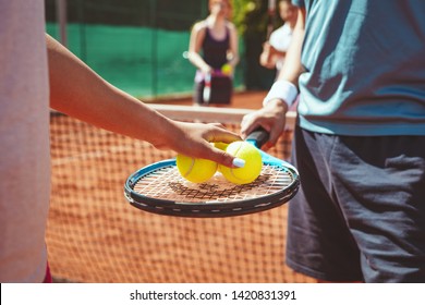 Close-up of a couple tennis player before serving to tennis match on outdoor clay court. Selective focus. Focus on a hands who holding ball and racket.