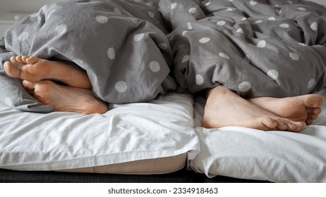 Closeup of couple's feet lying on bed and turning away from each other. Concept of family conflict and arguing, bad relations - Powered by Shutterstock