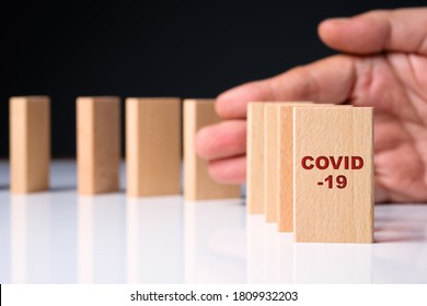 Closeup Covid-19 First Domino With Hand Prevent The Coming Of Falling Down, Resolve The Affected To Finance And Economic By Virus Pandemic