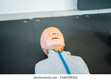 Close-up of a CPR training dummy placed on a mat, used for practicing lifesaving techniques, emergency response, and first aid skills in a classroom or training facility. - Powered by Shutterstock