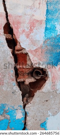 Close-up of a cracked wall featuring peeling plaster that exposes underlying red bricks, creating a layered and textured composition. Faded blue and white paint adds a worn, weathered look, enhancing the sense of age and history. A deep vertical fracture runs through the surface, drawing attention to structural detail and visual depth.

An exposed metal pipe emerges from the wall, introducing an industrial element that contrasts with the rough masonry. The combination of chipped plaster, uneven edges, and visible brickwork forms a rich, tactile surface filled with character. Subtle variations in tone and texture contribute to a realistic and engaging appearance.

This urban decay scene is ideal for backgrounds, texture libraries, and design projects focused on architecture, construction, and industrial themes. It also suits creative concepts related to aging structures, abandonment, and raw city environments.

High-resolution clarity ensures sharp detail across every element, from cracked paint layers to brick patterns and metallic surfaces. The composition remains balanced, allowing easy integration into digital and print designs.

Perfect for designers, photographers, and content creators, this distressed wall texture delivers a powerful combination of color contrast, structural detail, and rugged character, providing a unique visual foundation for a wide range of creative applications.