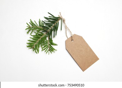 Close-up Of Craft Paper Gift Tag With Rope And Green Fir Branch Isolated On White Background. Christmas Composition, Top View.