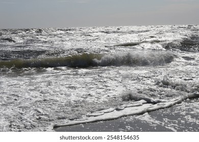 Close-up of crashing waves on the Black Sea, glistening in the sunlight with frothy sea foam along the shore. - Powered by Shutterstock