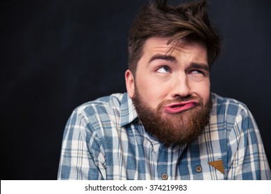 Closeup Of Crazy Young Man In Plaid Shirt Joking And Grimacing Over Black Background