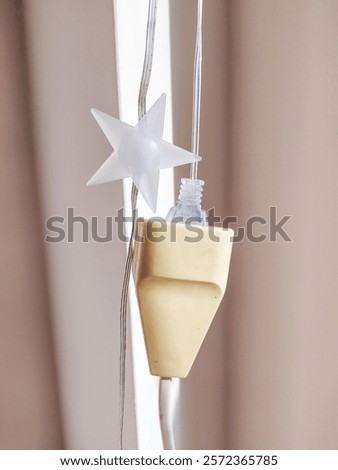 Closeup of a creamcolored electrical plug with a string of lights featuring starshaped bulbs.  Perfect for projects related to home d?cor, electricity, holidays, or DIY crafts.  Minimalist aesthetic.