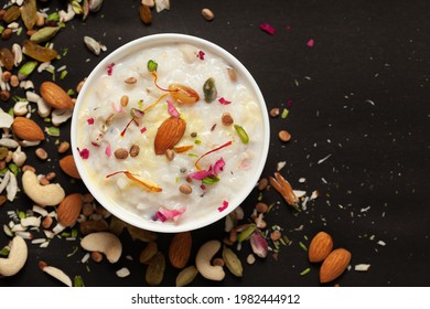 Close-up of Creamy rice Kheer(khir) Garnished with saffron and dry fruits. Indian delicious dessert. Served in white ceramic  bowl. Top View on black background. - Shutterstock ID 1982444912