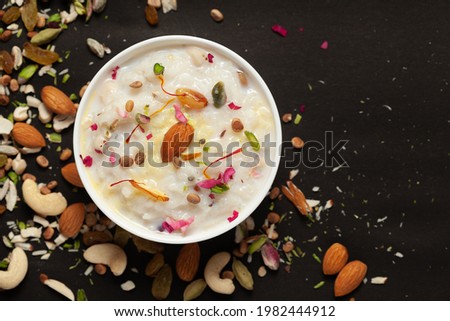 Close-up of Creamy rice Kheer(khir) Garnished with saffron and dry fruits. Indian delicious dessert. Served in white ceramic  bowl. Top View on black background.