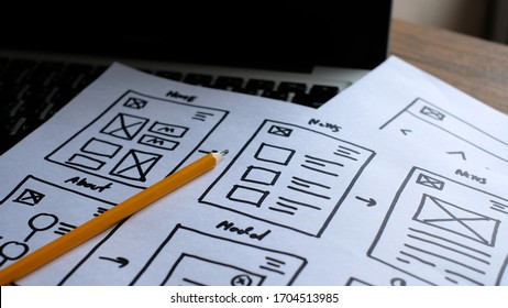Close-Up Creating mobile responsive website, wireframe sketches on designer desk.
