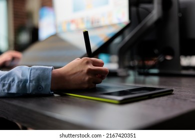Closeup of creative graphic designer using stylus pen and graphic tablet to edit photos. Digital photo editor sitting at desk with multiple displays while using editing software to retouch images. - Shutterstock ID 2167420351