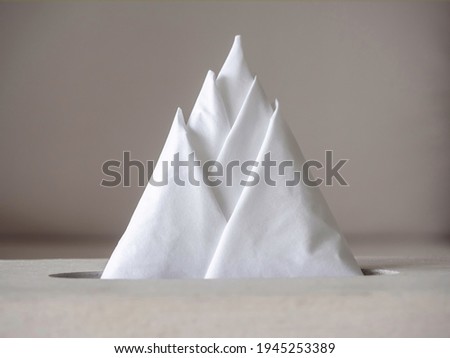 Close-up creative white clear tissue paper or napkins arranged in triangle mountain form in the box.