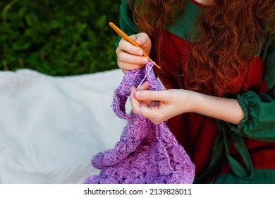 Close-up crochet. A woman with red hair is knitting a lilac shawl. Space for the text.