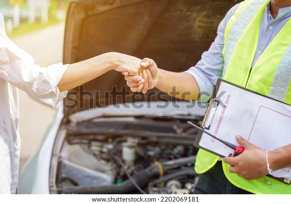 Closeup\
and crop of a congratulatory handshake of insurance employee and\
customer with sun flare on car engine\
background.