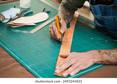 Closeup and crop hand of senior craftsman maker using cutter knife cut a leathers to make belts in workshop. - Powered by Shutterstock