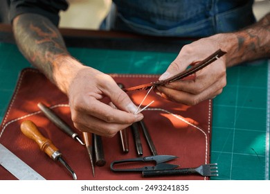 Closeup and crop hands of leather craftsman sewing and repair bag handle of leather brown bag for a customer in workshop. - Powered by Shutterstock