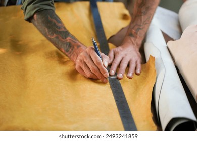 Closeup and crop hands of leather craftsman using a pencil and steel ruler drawing design on the yellow leather in the workshop. - Powered by Shutterstock