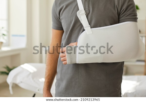 Closeup crop of injured man wear sling on broken\
leg. Unwell guy with protective bandage gear on arm, have injury or\
trauma. Rehabilitation concept. Healthcare and medicine. Health\
insurance cover.