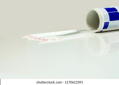 Closeup And Crop Of Medical Capillary Glass Tube Spread And Container On Gray Background., Designed For Both Safe Blood Collection As Well As Accurate Micro-hematocrit Determinations Precision.